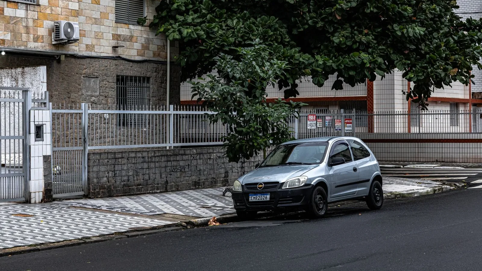 Rua urbana ao entardecer com céu alaranjado entre prédios