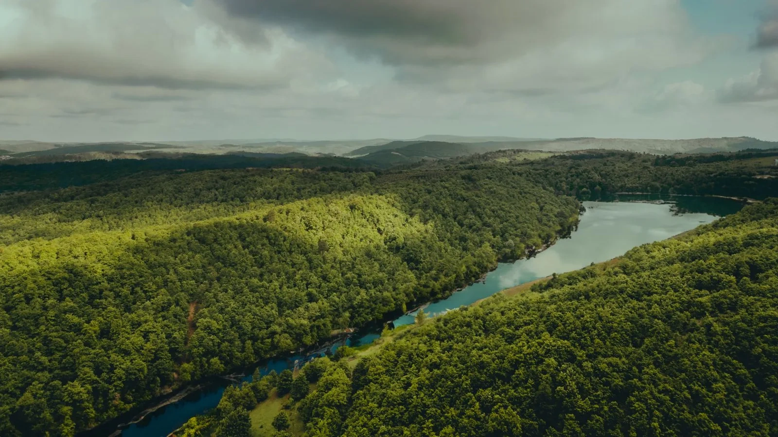 Vista aérea de um rio fazendo uma curva entre colinas verdes
